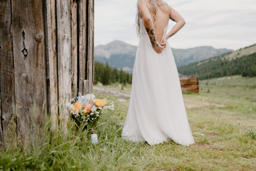 woman zipping up wedding gown