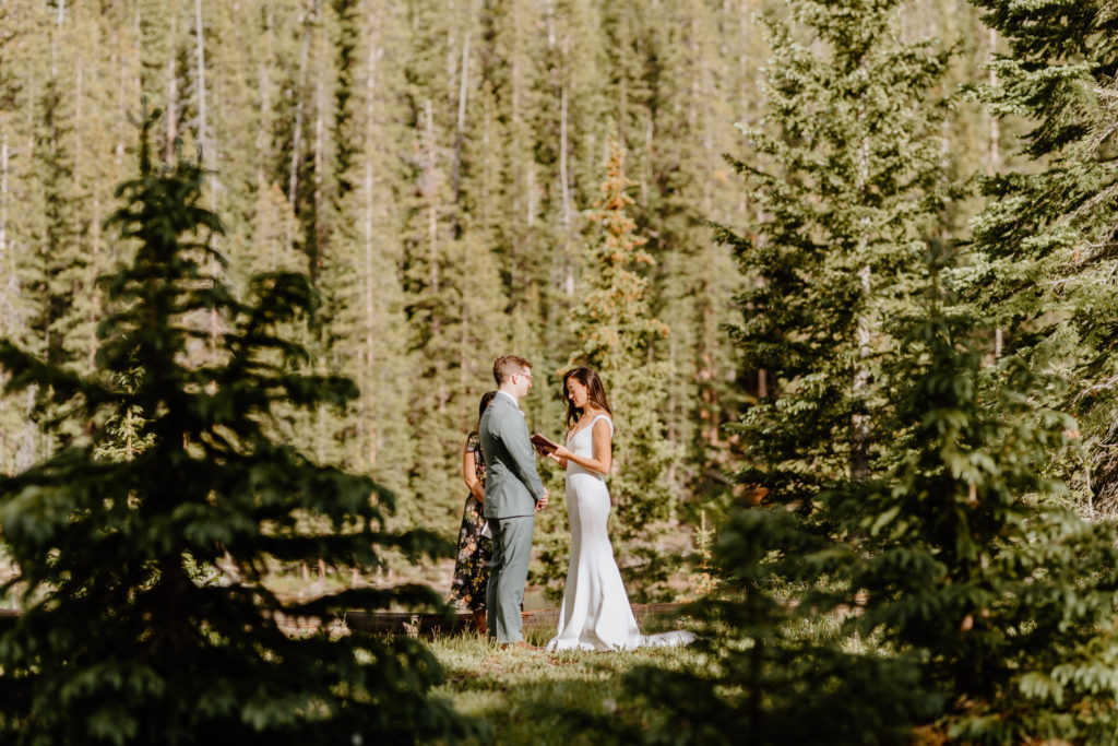 Couple reading vows surrounded by thick forest trees