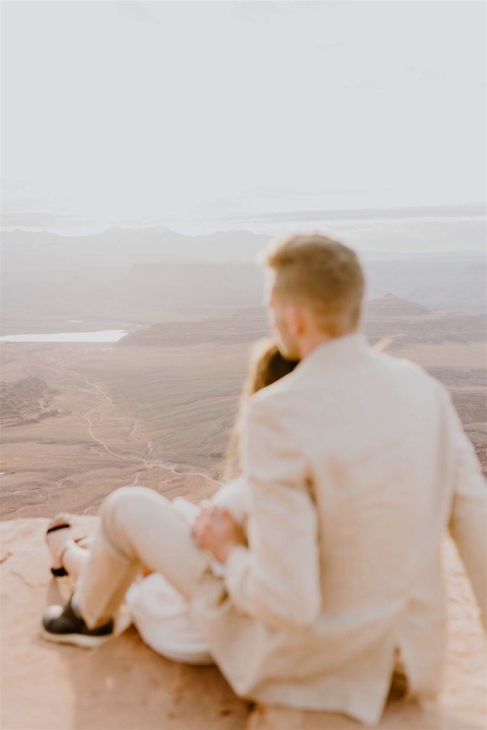 couple sitting on a ledge overlooking the desert