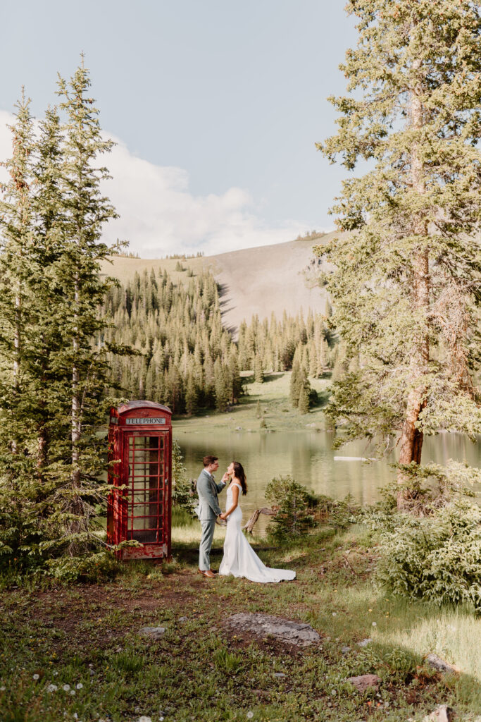 couple standing and kissing near alpine lake on wedding day
