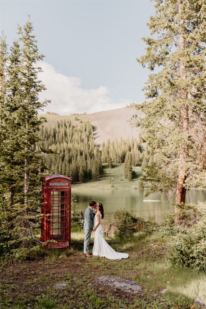couple kissing next to telephone booth by lake