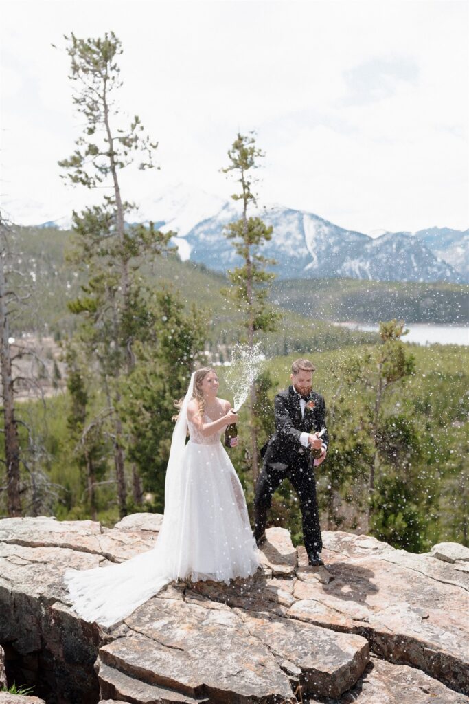 Couple pops champagne on a mountain overlook to celebrate marriage