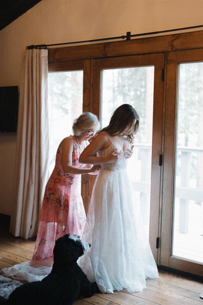 Bride's mother helps her button up wedding gown