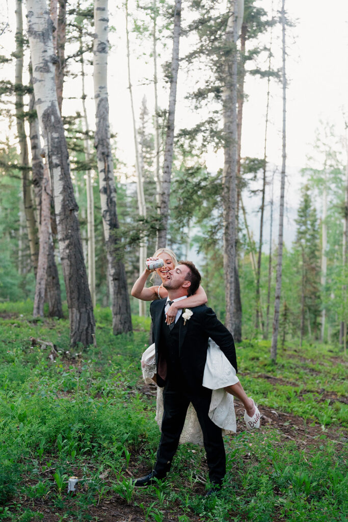 Bride and groom crack open a beer in the forest to celebrate their wedding in Telluride