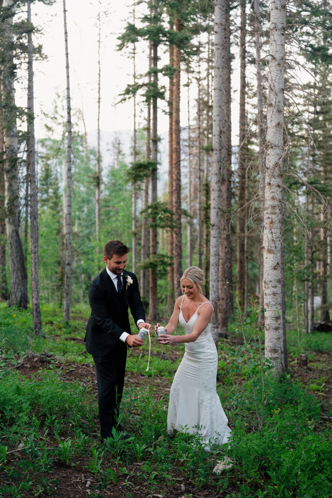 Bride and groom crack open a beer in the forest to celebrate their wedding in Telluride