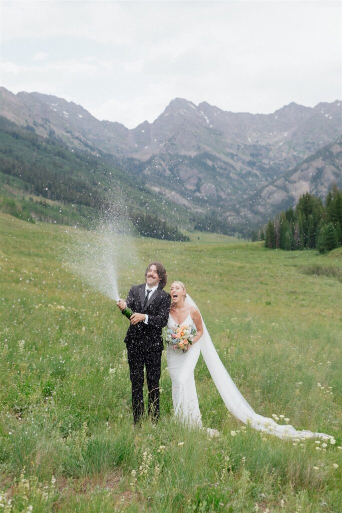 Bride and groom pop champagne during their Colorado micro wedding