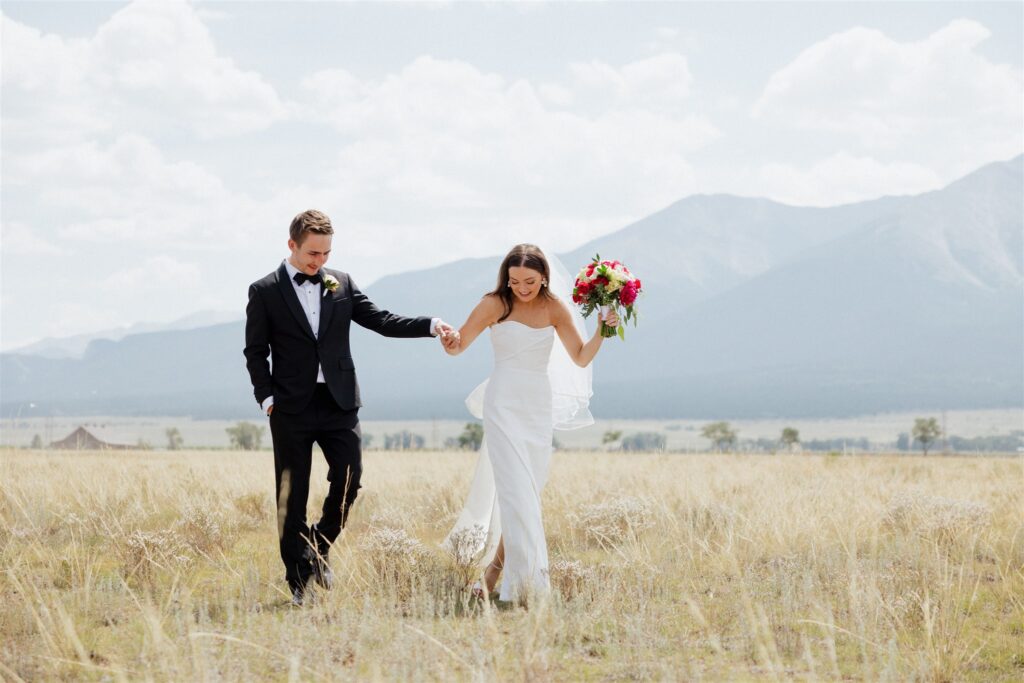 Bride and groom walk through a field in Buena Vista