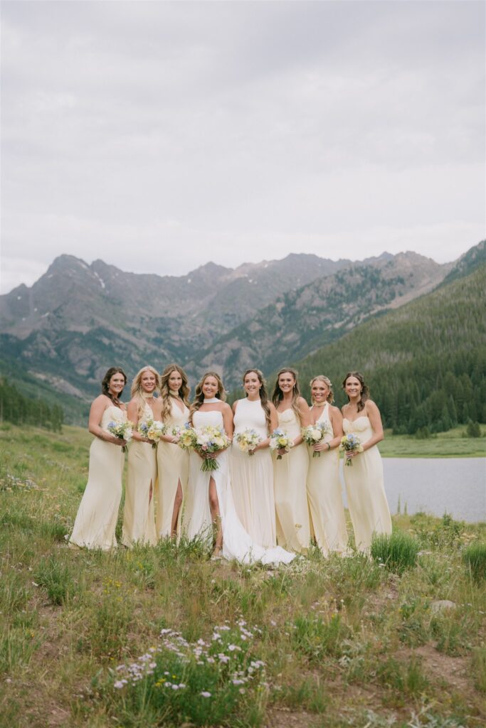 Bride stands with bridesmaids wearing butter yellow dresses at Piney Lake