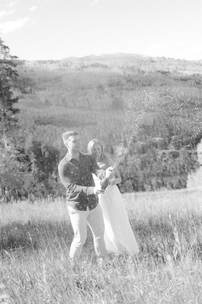 Mountain engagement photos in Colorado popping champagne