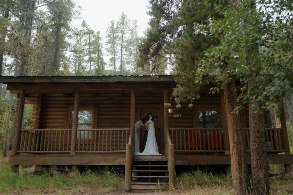Bride gets dressed at a log cabin in the woods before her Camp Hale ceremony