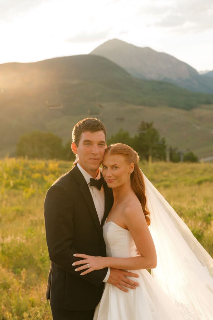 Bride and groom stand in a mountain meadow in Crested Butte Colorado during sunset