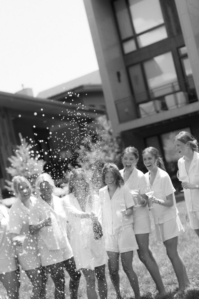 Bride pops champagne with bridesmaids before they get ready