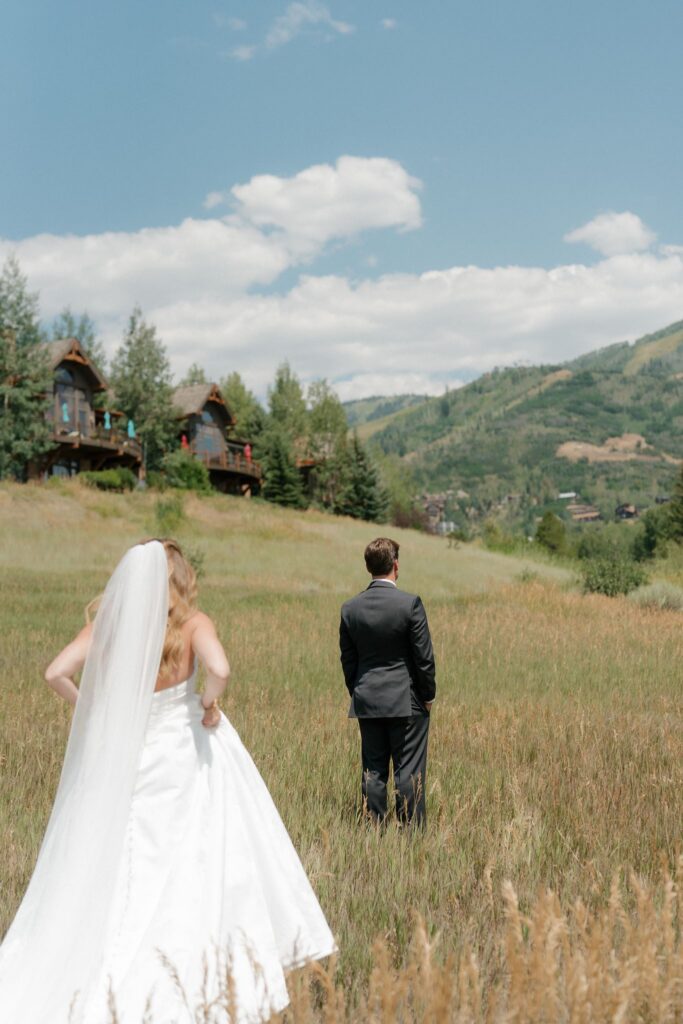 Steamboat Springs bride and groom first look in a green field with blue summer skies