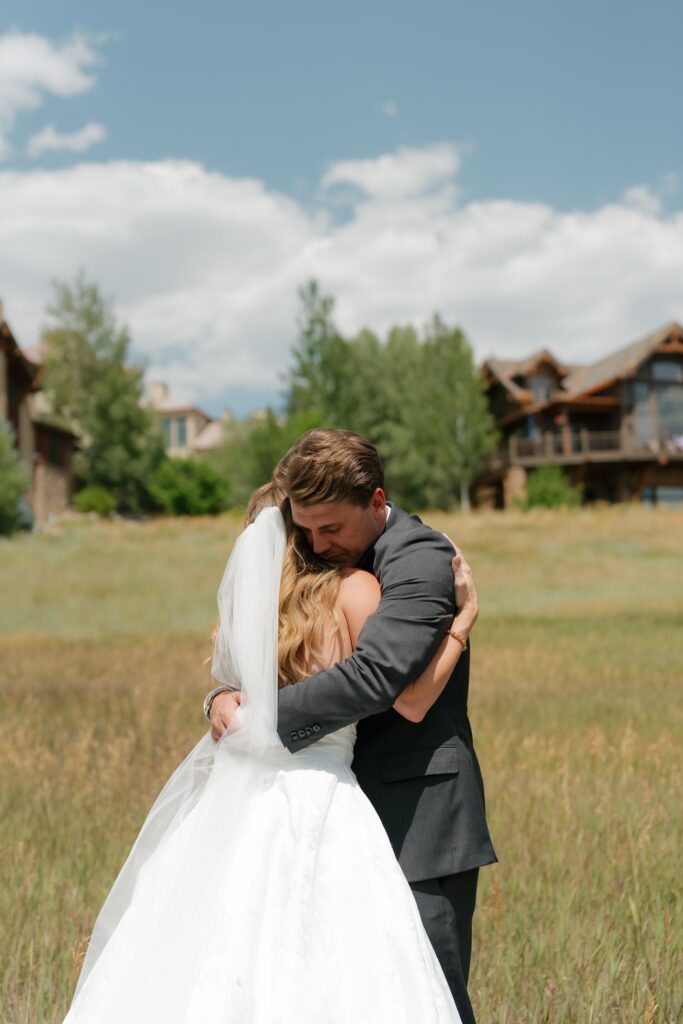 Steamboat Springs bride and groom first look in a green field with blue summer skies